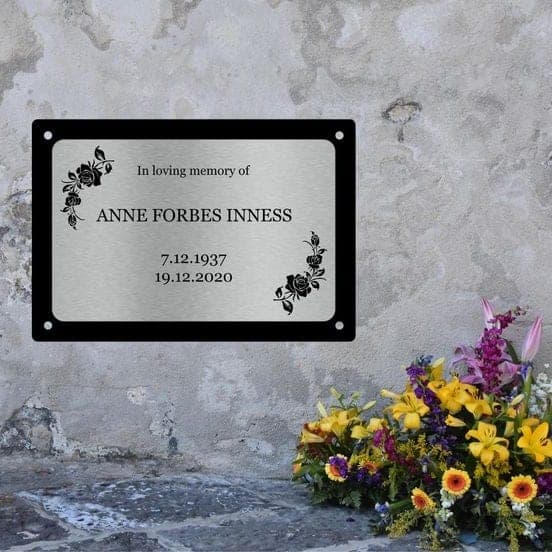 Autocollant QR code apposé sur une plaque commémorative fixée à un mur de pierre